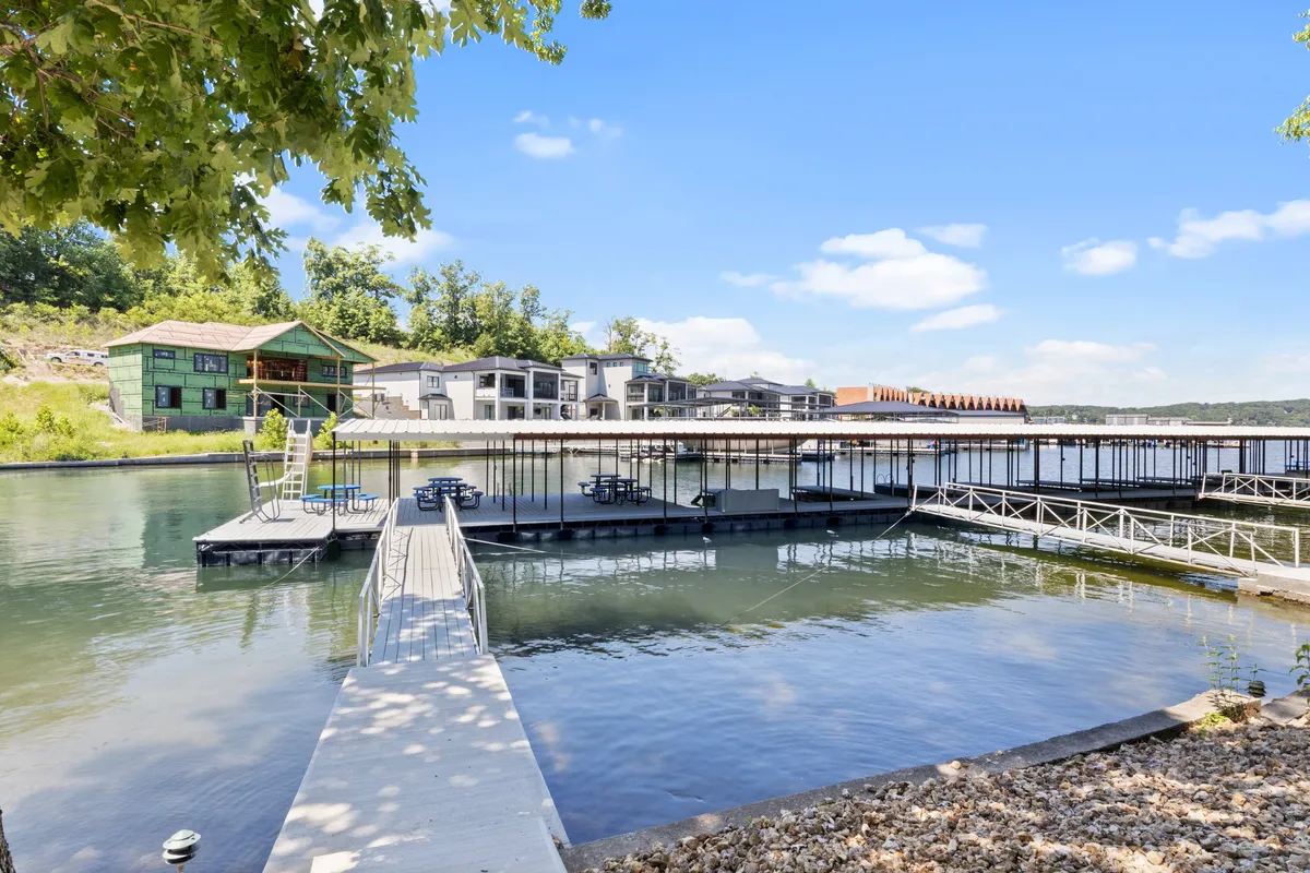 A panoramic view of the dock and waterfront, framed by surrounding greenery and modern condo buildings. The image captures a tranquil moment on the dock, perfect for peaceful mornings, sunset relaxation, or social events by the water.