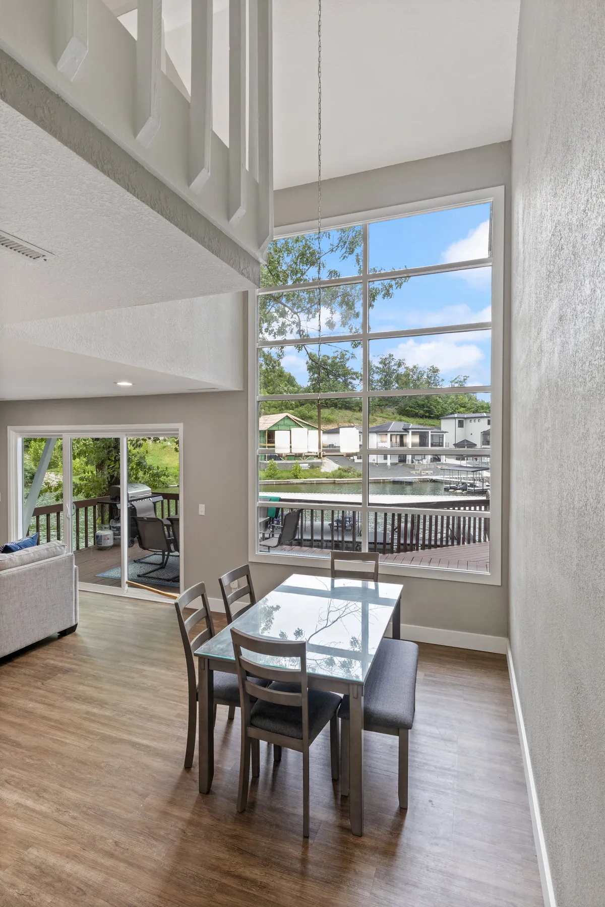 A dining space bathed in natural light from large windows, featuring a dining table set for family meals and a view of the nearby deck. The setting blends indoor comfort with hints of outdoor beauty, suggesting relaxed meals with a view.