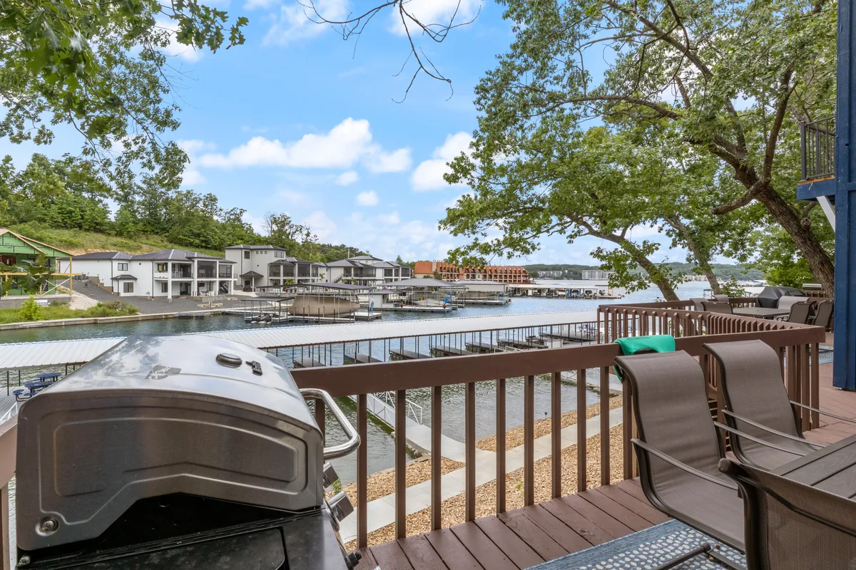 A scenic waterfront seating area with a grill and views of the water and boathouses, inviting guests to relax, barbecue, or simply soak in the lakeside ambiance while the sun sets.