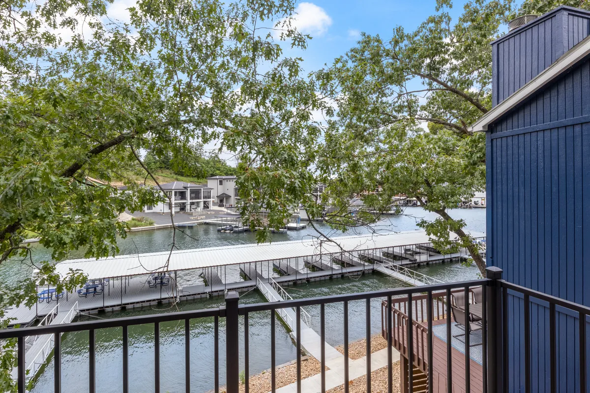 A picturesque marina scene with multiple docks, calm water, and a backdrop of trees and a blue building. The setting invites boating, fishing, group hangouts on the dock, and peaceful moments by the waterfront.